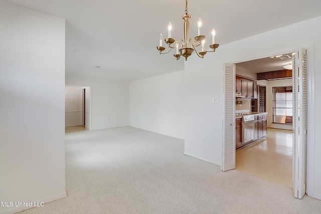 carpeted empty room with an inviting chandelier