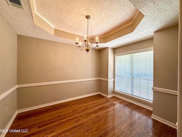 spare room with an inviting chandelier, ornamental molding, dark wood-type flooring, and a raised ceiling