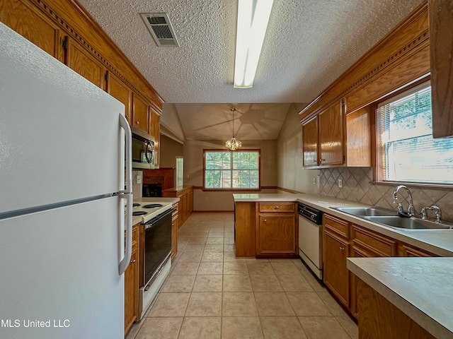 kitchen with kitchen peninsula, vaulted ceiling, pendant lighting, sink, and white appliances