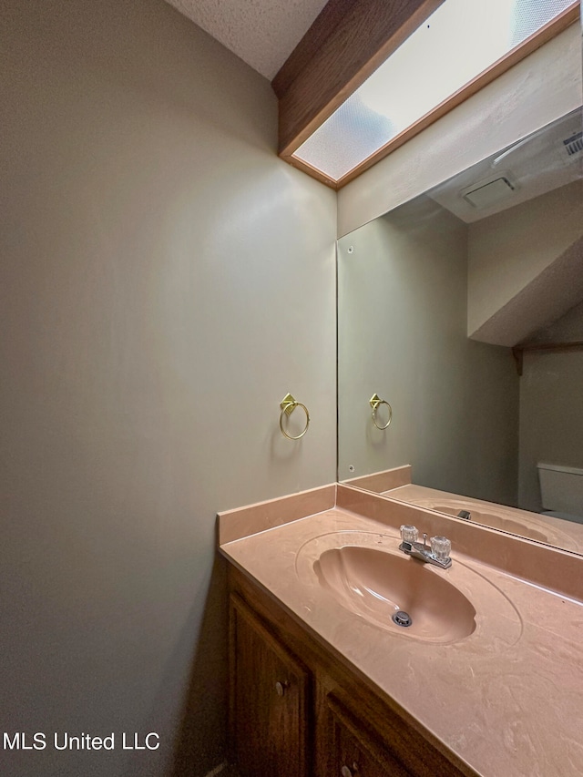 bathroom featuring vanity, a textured ceiling, and a skylight