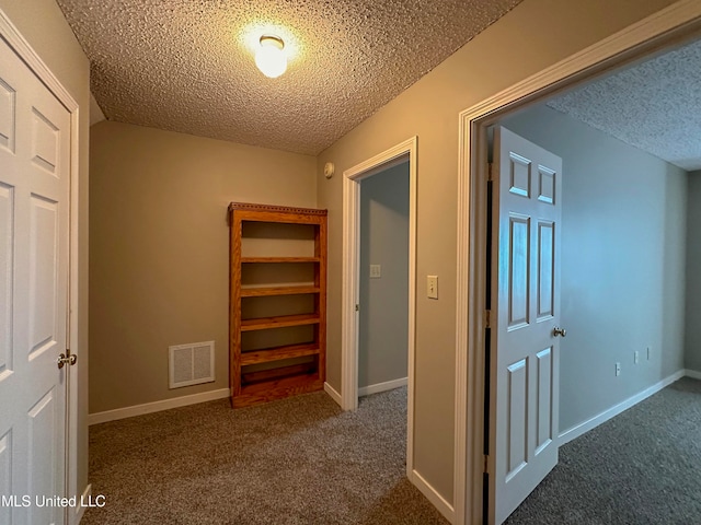 hall with a textured ceiling and carpet floors