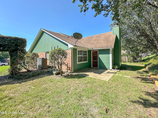 rear view of house with a patio area, cooling unit, and a yard