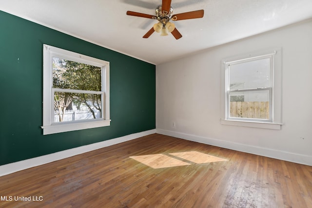 spare room featuring baseboards, ceiling fan, and hardwood / wood-style flooring