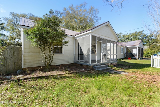 view of front of property with fence, a sunroom, a front lawn, crawl space, and metal roof