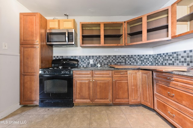 kitchen with gas stove, stainless steel microwave, backsplash, and light tile patterned flooring