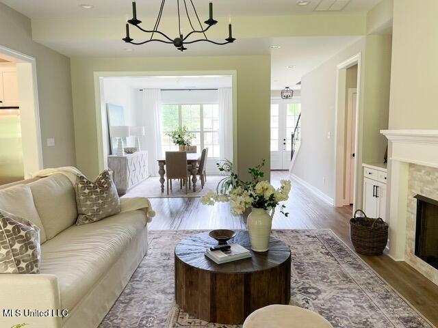 living room with hardwood / wood-style flooring, a tile fireplace, and an inviting chandelier