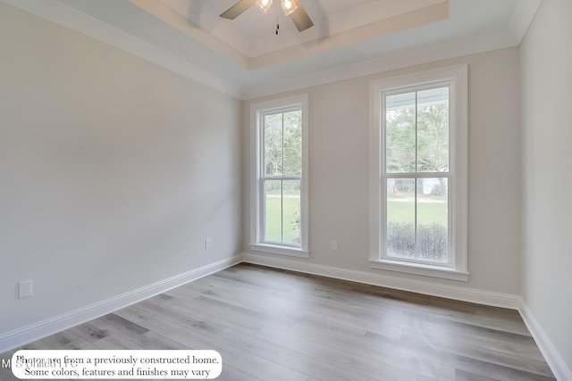spare room with a ceiling fan, baseboards, a raised ceiling, and light wood-style floors