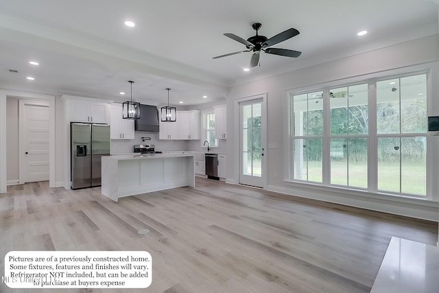 kitchen featuring appliances with stainless steel finishes, white cabinetry, light countertops, ornamental molding, and wall chimney exhaust hood