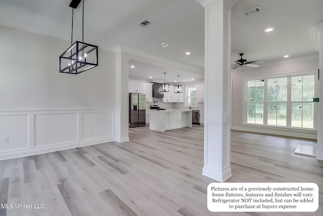 unfurnished living room featuring wainscoting, a decorative wall, ceiling fan with notable chandelier, recessed lighting, and ornamental molding