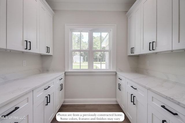 interior space with white cabinets, baseboards, light stone counters, and dark wood-type flooring