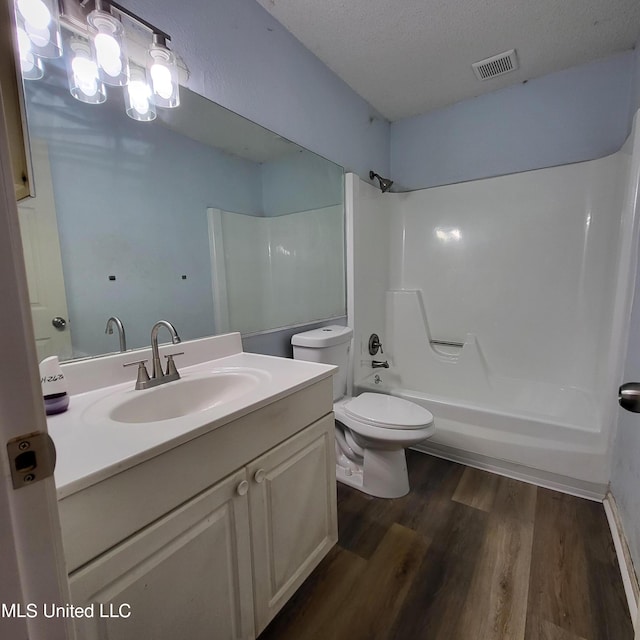 full bathroom with vanity, a textured ceiling, shower / washtub combination, wood-type flooring, and toilet