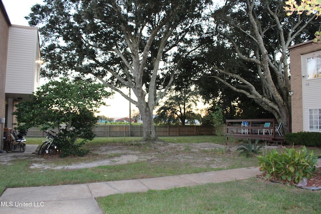 yard at dusk featuring a wooden deck