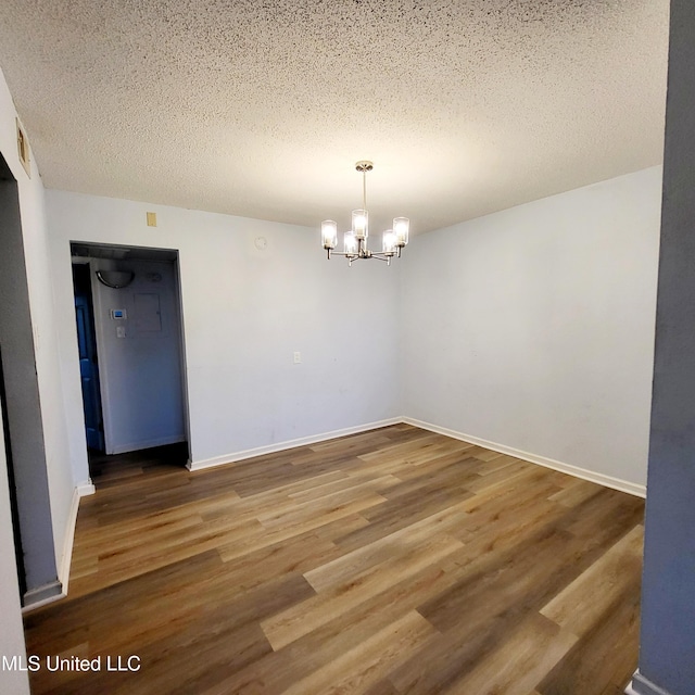 spare room featuring hardwood / wood-style floors, a textured ceiling, and a notable chandelier