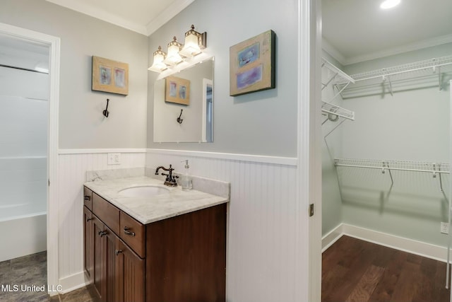 bathroom featuring a wainscoted wall, a spacious closet, wood finished floors, and vanity