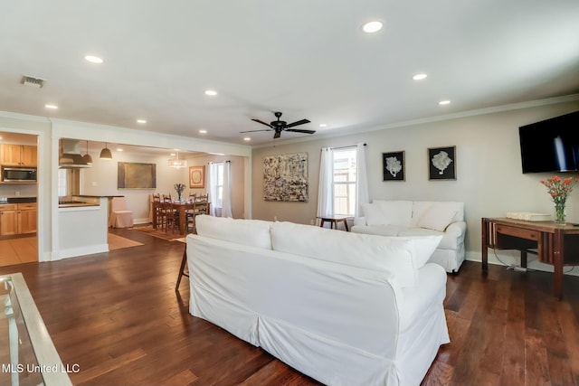 living room with crown molding, visible vents, dark wood-type flooring, and recessed lighting