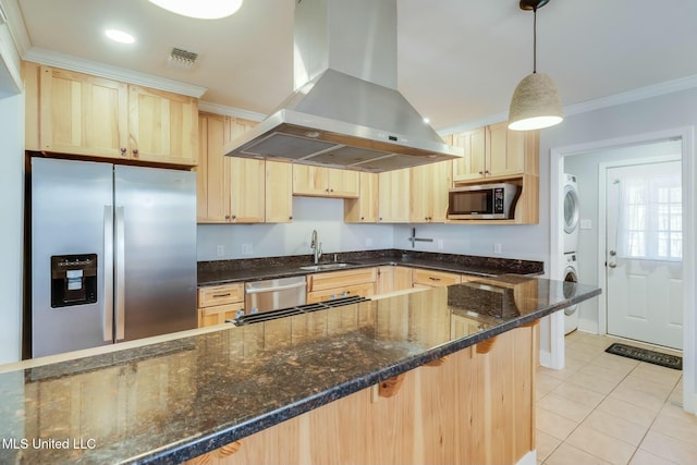 kitchen featuring stacked washer and dryer, stainless steel appliances, wall chimney range hood, light brown cabinets, and a sink