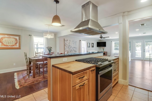 kitchen featuring plenty of natural light, stainless steel gas stove, wooden counters, and island range hood