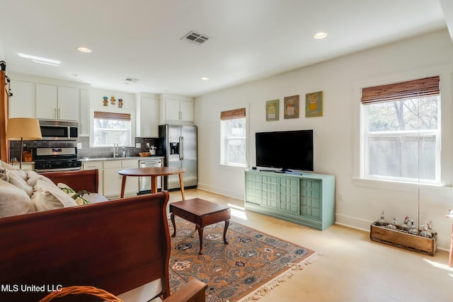 living area with baseboards, visible vents, and recessed lighting