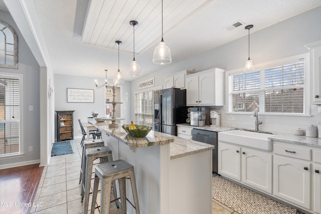 kitchen with decorative light fixtures, dishwasher, a kitchen island, and white cabinets