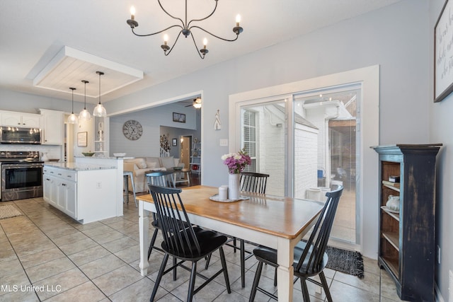 tiled dining space with ceiling fan with notable chandelier