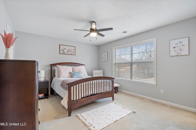 carpeted bedroom featuring ceiling fan and a textured ceiling