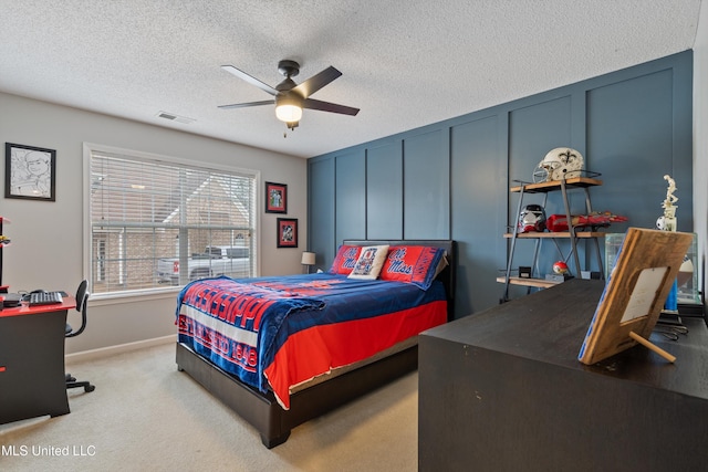 bedroom with ceiling fan, light carpet, and a textured ceiling