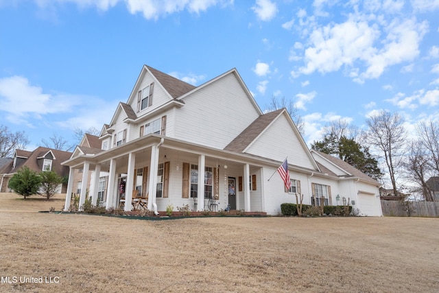 view of front of property featuring a garage, a front lawn, and covered porch