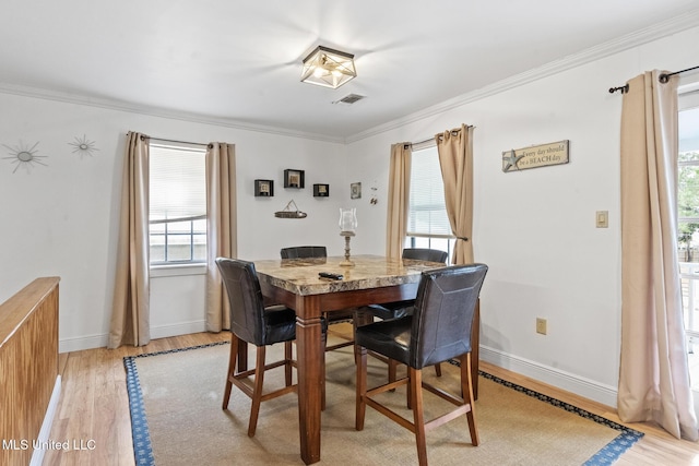 dining room with baseboards, light wood-style floors, visible vents, and crown molding