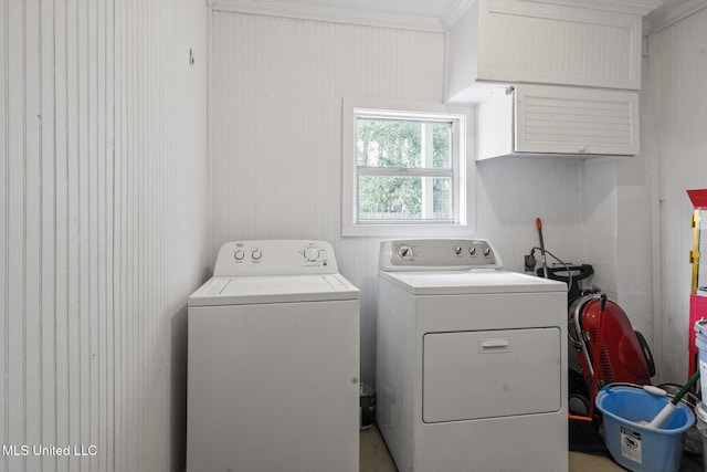 laundry area with ornamental molding, washing machine and dryer, and cabinet space