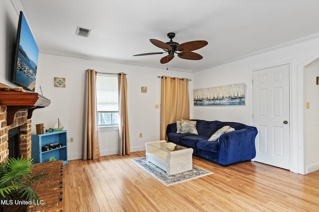 living room with crown molding, a fireplace, visible vents, and wood finished floors