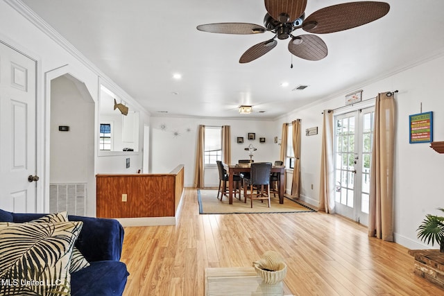 living room with light wood-style flooring, visible vents, and crown molding