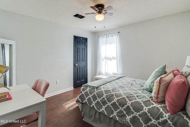 bedroom with dark wood finished floors, visible vents, a ceiling fan, a textured ceiling, and baseboards