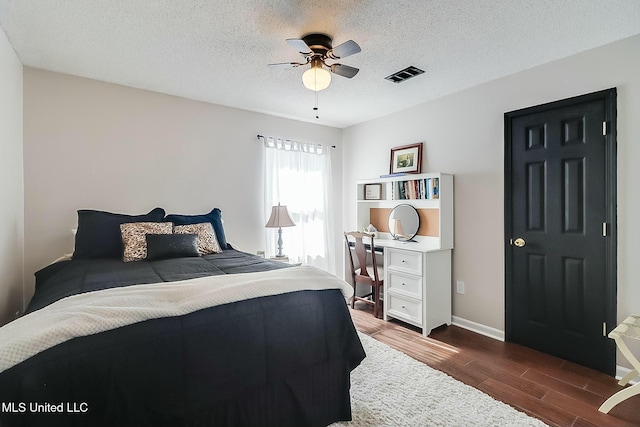 bedroom featuring visible vents, dark wood-type flooring, a ceiling fan, a textured ceiling, and baseboards