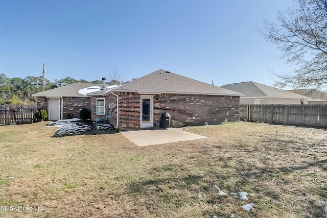 back of property with roof with shingles, brick siding, a patio, a lawn, and a fenced backyard