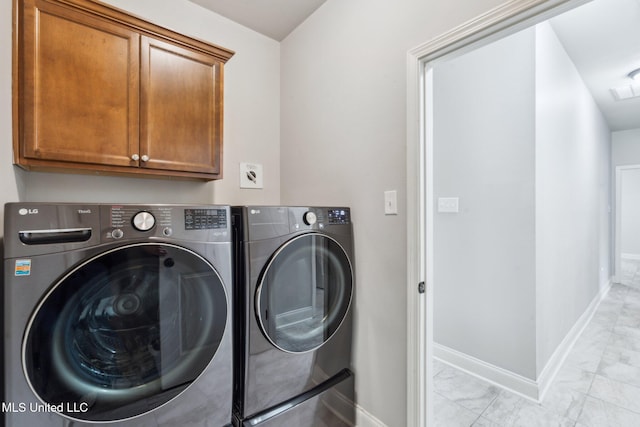 clothes washing area featuring cabinets and washing machine and clothes dryer