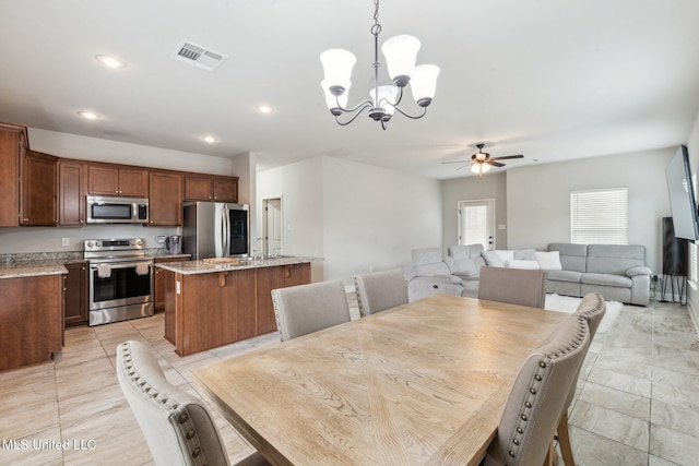 dining space with sink and ceiling fan with notable chandelier