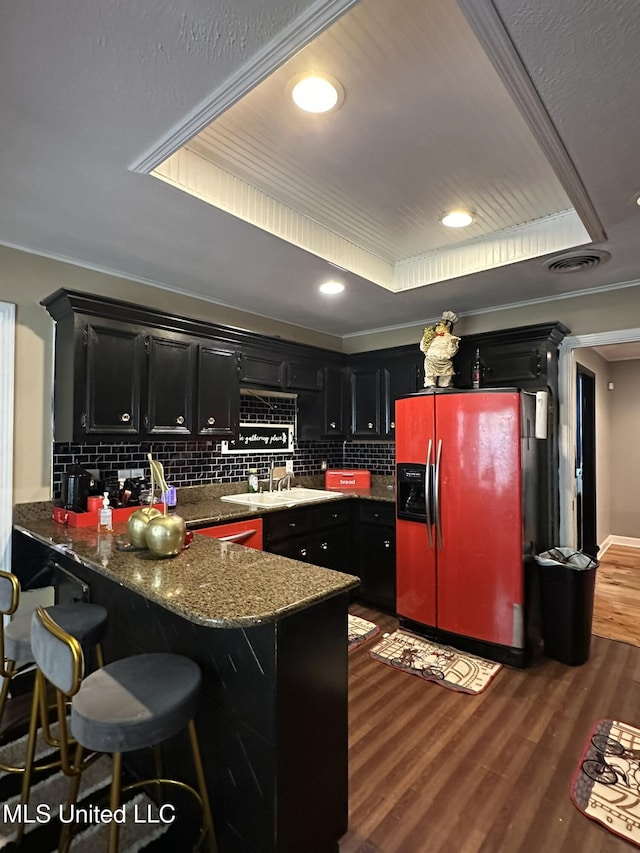 1052 Briarfield Rd, Jackson, MS 39211 - kitchen featuring fridge with ice dispenser, dark cabinets, a sink, a peninsula, and decorative backsplash