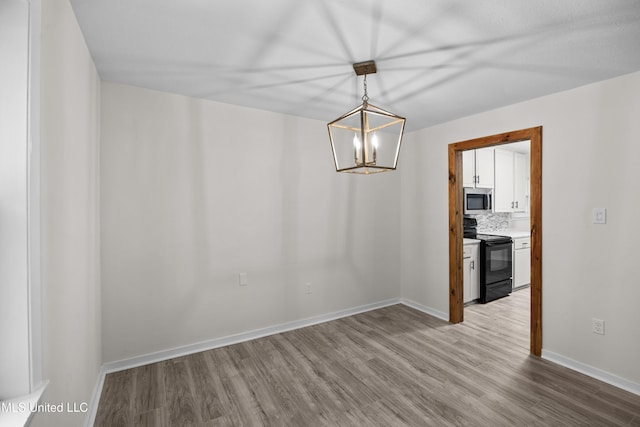 2389 Napoleon Ave, Pearl, MS 39208 - unfurnished dining area featuring wood finished floors, baseboards, and an inviting chandelier