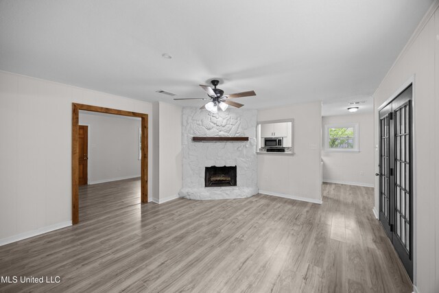 2389 Napoleon Ave, Pearl, MS 39208 - unfurnished living room featuring a fireplace, light wood finished floors, a ceiling fan, and baseboards