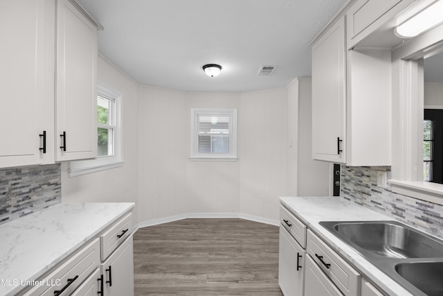 2389 Napoleon Ave, Pearl, MS 39208 - kitchen featuring light wood finished floors, a sink, baseboards, backsplash, and white cabinetry
