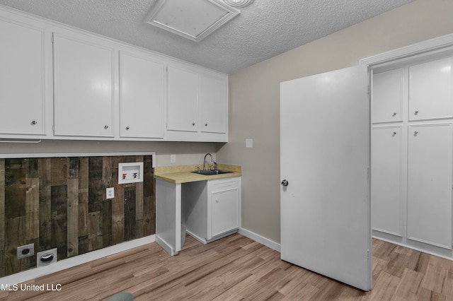 clothes washing area with cabinets, light hardwood / wood-style flooring, sink, and electric dryer hookup