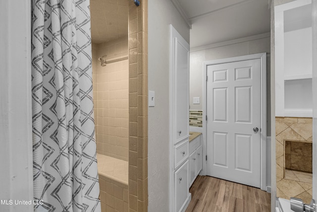 bathroom with hardwood / wood-style flooring, ornamental molding, vanity, curtained shower, and tile walls