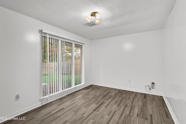 spare room with a textured ceiling and wood-type flooring