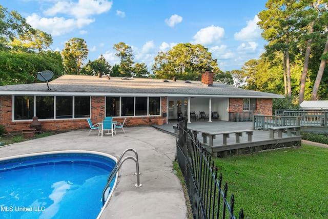 back of property with a patio area, a pool side deck, and a lawn