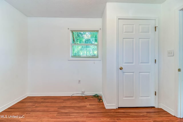 empty room with light hardwood / wood-style floors and a textured ceiling