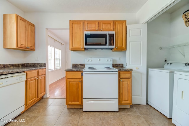 kitchen with white appliances, a textured ceiling, light tile patterned floors, and washing machine and clothes dryer