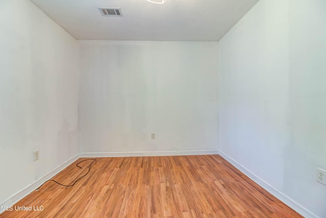 spare room featuring a textured ceiling and light wood-type flooring