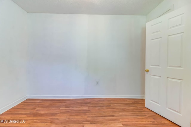 empty room featuring a textured ceiling and light hardwood / wood-style flooring