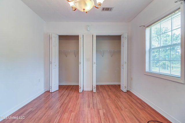 unfurnished bedroom featuring light hardwood / wood-style floors and multiple closets