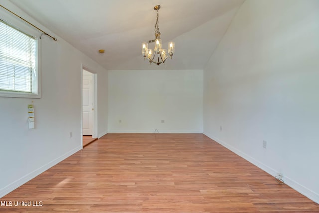 unfurnished room featuring a notable chandelier, vaulted ceiling, and light wood-type flooring